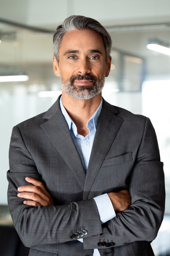 Handsome hispanic senior business man with crossed arms smiling at camera
